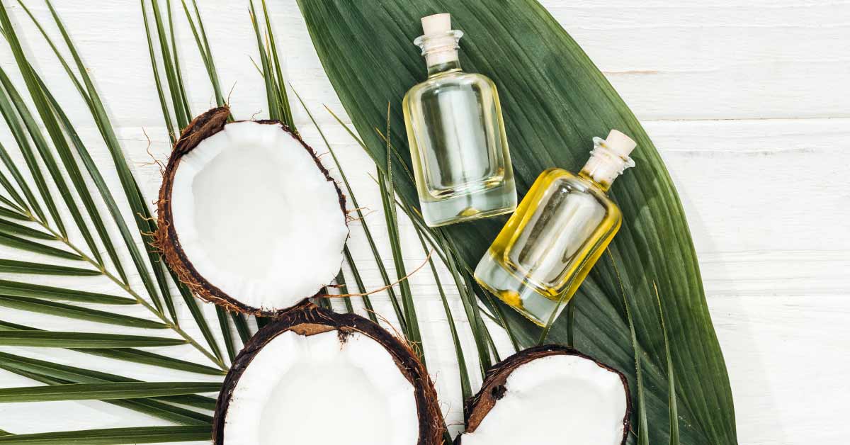 aceite de coco en frascos de cristal sobre hojas de palmera