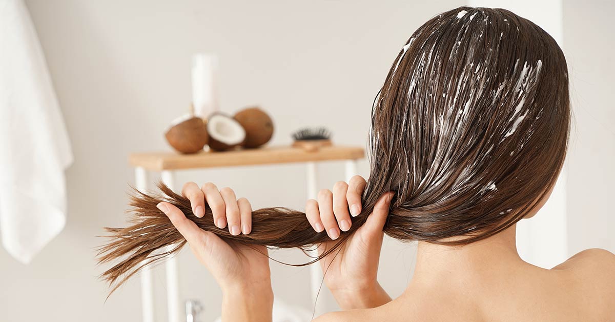 mujer tomandose el cabello con shampoo a base de coco