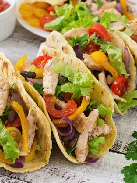 Mexican tacos with chicken, bell peppers, black beans and fresh vegetables